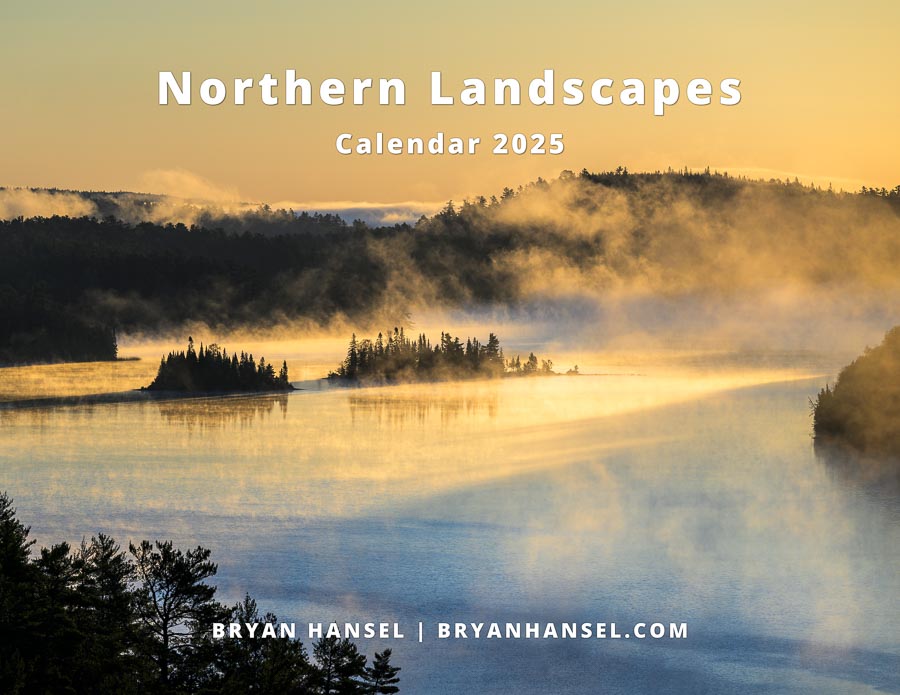 The cover of Bryan Hansel's 2025 Calendar. It shows a steaming lake with two islands under a yellow sunrise sky.